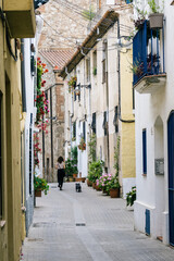 Fototapeta na wymiar Woman walking a dog in a narrow street in the old quarter