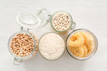 Glass jars with different products on light background