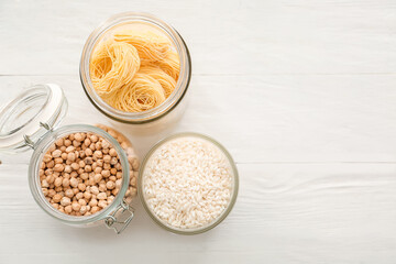 Glass jars with different products on light wooden background
