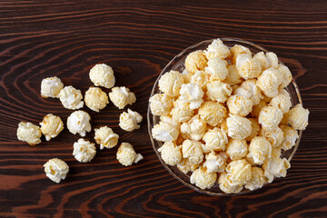 Fresh, sweet popcorn with caramel, golden color on the background of a dark wooden table, top view