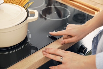 Woman turning on kitchen stove, closeup