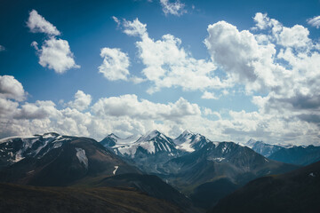 Fototapeta premium Awesome alpine view to big snowy mountains with glacier. Wonderful highland scenery with great snowy mountains and clouds in blue sky. Amazing mountain landscape with glaciers and melt water streams.