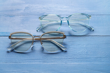 Different stylish eyeglasses on color wooden background