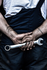 Dirty car mechanic's hands with a key.