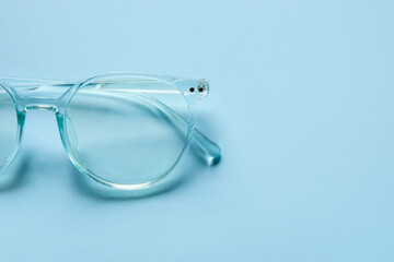 Stylish eyeglasses on color background, closeup