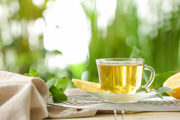 Grid with cup of tasty green tea and ingredients on table outdoors