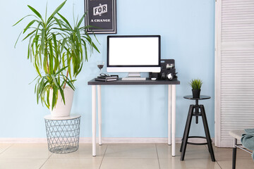 Stylish workplace with modern computer on table near color wall