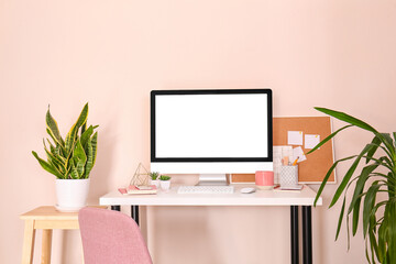Stylish workplace with modern computer on table near color wall