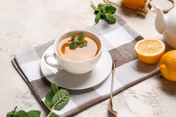 Cup of tasty green tea, pot and ingredients on grunge background