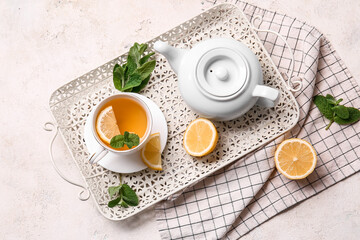 Tray with cup of tasty green tea, pot and ingredients on grunge background