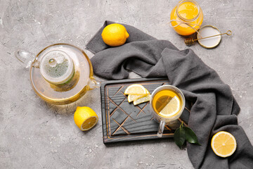 Wooden board with cup of tasty green tea and ingredients on grey background