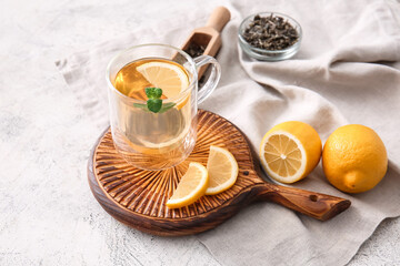 Wooden board with cup of tasty green tea and ingredients on light table