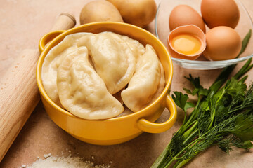 Pot with tasty dumplings and fresh ingredients on grunge background