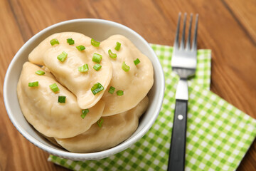 Bowl with tasty dumplings on wooden background