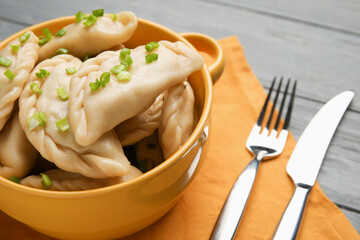 Pot with tasty dumplings on color wooden background, closeup