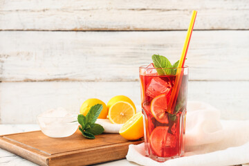 Glass of tasty ice tea with lemon on light background