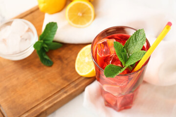 Glass of tasty ice tea with lemon on light background