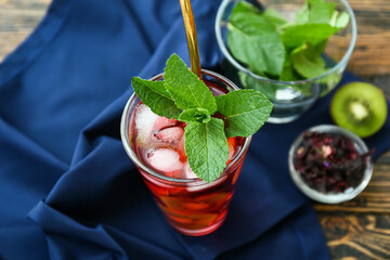 Glass of tasty ice tea with fruits on wooden background © Pixel-Shot