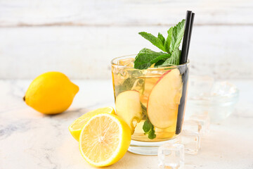 Glass of tasty ice tea with fruits on light background