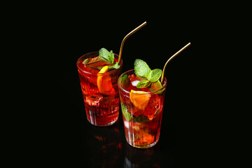 Glasses of tasty ice tea with fruits on dark background