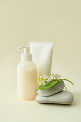 Composition with cosmetic products, stones and lily-of-the-valley flowers on color background