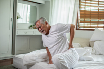 Asian Elderly senior man back pain and illness on bed at home,unhappy elderly touch on back serious and tried,Elderly Care Concept