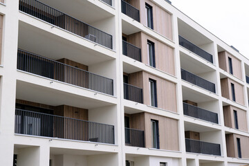 Exterior of new modern white apartment building with balcony in contemporary residential district.