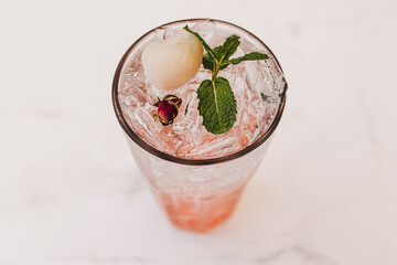 Lychee Pink Rose Italian Soda in transparent glass decorated with Mint leaves.
