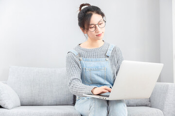 Asian girl sitting on sofa with glasses using computer