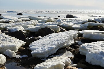 Ice jam on the coast sandy rocky beach. Gulf of Finland. Clear spring sunny blue sky. High quality photo