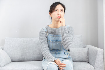 Asian girl sitting on sofa feeling uncomfortable nose