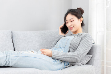 Asian girl lying on the sofa playing with mobile phone
