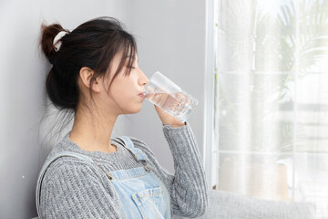Asian girl sitting on sofa drinking water