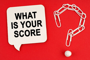 On a red background are a question mark made of paper clips and a sign with the inscription - WHAT IS YOUR SCORE