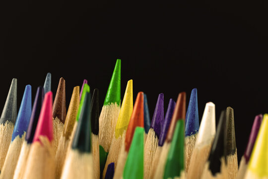 Closeup shot of the sharp tips of colorful school pencils on a black background, copy space photo