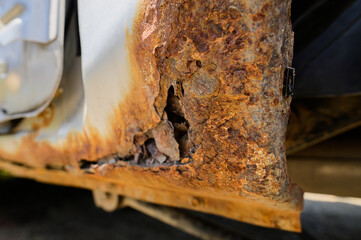 Fragment of a car body with rust. fragment of a rusty wing of a car. The body element is corroded. Concept: corrosion resistance, body repair, rust. Protection.