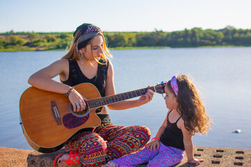 mamá e hija cantando y tocando la guitarra al aire libre 