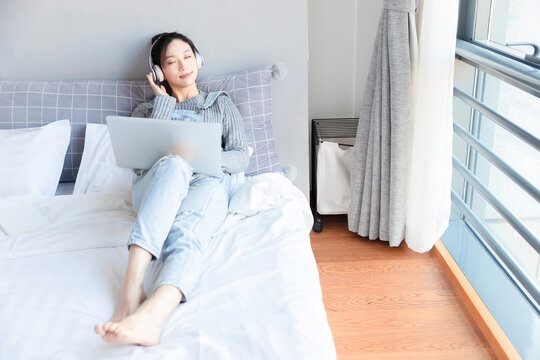 Asian Girl Looking At Computer In Bed