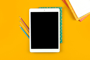 Education concept, students tablet with pencils on the yellow desktop, books with question signs, flat lay and top view photo