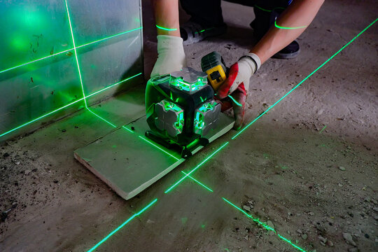 the builder measures the repair lines using a green laser level