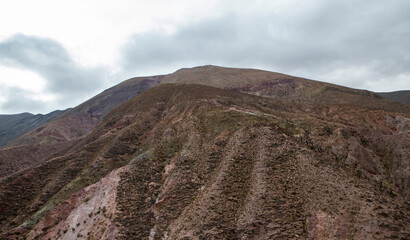 The Andes mountains in summer. The peak of the brown mountain under a cloudy sky. 