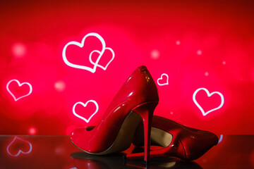 patent shiny female red stiletto heels on blurred background with hearts