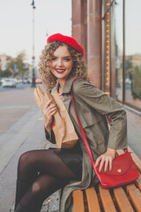 Happy attractive woman smiling and turning back at us in the street. Woman in red beret and red handbag outdoor