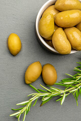 Green olives. Bella di cerignola Italian olives. Colored olives and a sprig of rosemary lie on a...
