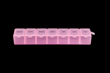 Pink plastic organizer for pills isolated on black background. Close-up of a case with clamping...