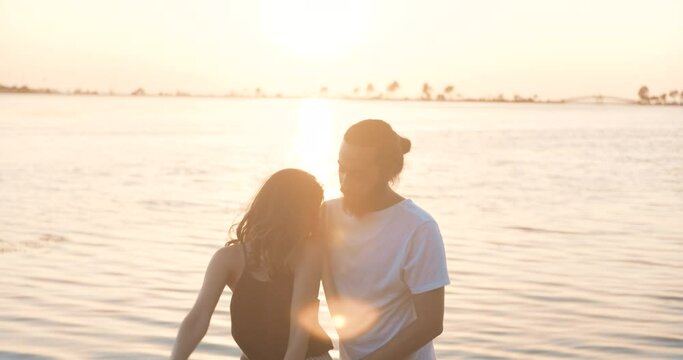 Romantic young couple is dancing on seaside, beach in golden hour sunset. Happy woman and man's relationship. Happiness, relaxing concept.