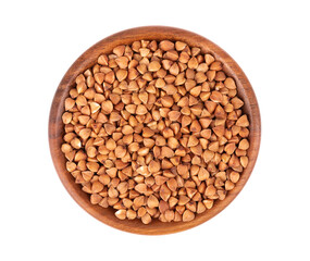 Roasted buckwheat grains in wooden bowl, isolated on white background. Dry brown buckwheat groats. Top view.