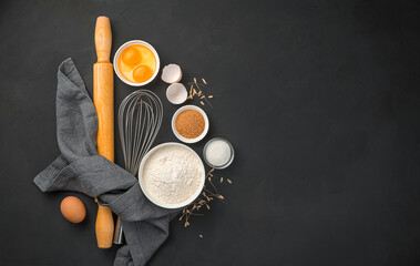Flour, eggs, sugar and rolling pin on a black background. Culinary background, baking.