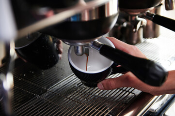 Close-up of espresso pouring from steam coffee machine into cups. Professional coffee brewing.