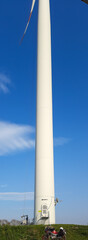 Der lange dicke weiße Stamm einer Windenergieanlage vor blauem Himmelhintergrund. Renewable Energy Concept Image . Windenergieanlage in Lang . Froschperspektive bottom view auf ein Windrad . Windmühle